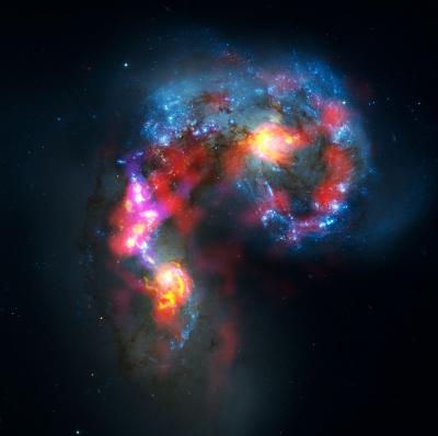 天线星系(又名NGC 4038和4039)是一对扭曲的螺旋星系，距离我们约7000万光年，位于乌鸦星座。这幅图结合了在天文台早期测试阶段以两种不同波长范围进行的ALMA观测，以及来自美国宇航局/欧洲航天局哈勃太空望远镜的可见光观测